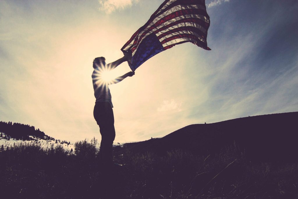 Man with American flag flying in the wind