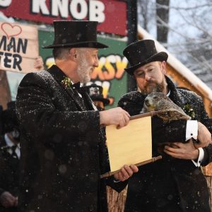 Groundhog Club handler A.J. Dereume holds Punxsutawney Phil, the weather prognosticating groundhog, as Vice President Tom Dunkel reads the scroll during the 135th celebration of Groundhog Day on Gobbler's Knob in Punxsutawney, Pa. Tuesday, Feb. 2, 2021. Phil's handlers said that the groundhog has forecast six more weeks of winter weather during this year's event that was held without anyone in attendance due to potential COVID-19 risks. (AP Photo/Barry Reeger)