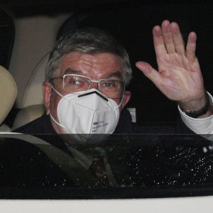 International Olympic Committee (IOC) President Thomas Bach waves from the vehicle to media upon his arrival an accommodation Thursday, July 8, 2021, in Tokyo. Bach arrived on Thursday, July 8, 2021, in Tokyo as Japan Prime Minister Yoshihde Suga was set to declare a state of emergency that is likely to result in a ban on fans from the Tokyo Olympics as coronavirus infections spread across the capital. (AP Photo/Eugene Hoshiko, Pool)