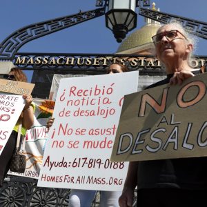 People from a coalition of housing justice groups hold signs protesting evictions during a news conference outside the Statehouse, Friday, July 30, 2021, in Boston. (AP Photo/Michael Dwyer)