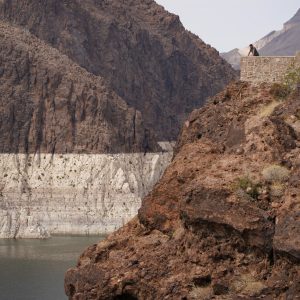 A person looks out over Lake Mead near Hoover Dam at the Lake Mead National Recreation Area, Friday, Aug. 13, 2021, in Arizona. The bathtub ring of light minerals shows the high water mark of the reservoir which has fallen to record lows. (AP Photo/John Locher)