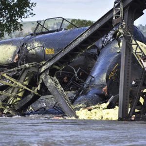 Several train cars are immersed in the Yellowstone River after a bridge collapse near Columbus, Mont., on Saturday, June 24, 2023. The bridge collapsed overnight, causing a train that was traveling over it to plunge into the water below. Authorities on Sunday were testing the water quality along a stretch of the Yellowstone River where mangled cars carrying hazardous materials remained after crashing into the waterway. (AP Photo/Matthew Brown)