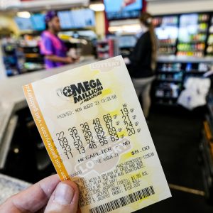A Mega Millions ticket is seen as a person makes a purchase inside a convenience store, ahead of Tuesday's Mega Millions drawing of $1.55 billion, Monday, Aug. 7, 2023, in Kennesaw, Ga. There now have been 31 straight drawings without a big jackpot winner. (AP Photo/Mike Stewart)