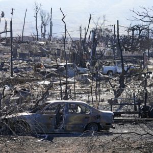 Destroyed homes and cars are shown, Sunday, Aug. 13, 2023, in Lahaina, Hawaii. Hawaii officials urge tourists to avoid traveling to Maui as many hotels prepare to house evacuees and first responders on the island where a wildfire demolished a historic town and killed dozens. (AP Photo/Rick Bowmer)