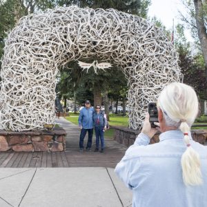 Nathan Davis of Flat Rock, MI., takes a photo of John and Debbie Oder of South Lyon, MI., in front of the antler arches of Town Square in Jackson, WY. on Aug. 23, 2023. After two years of a red-hot post-pandemic recovery Jackson is returning to something like normal, with sustainable spending and less inflationary conditions the Federal Reserve would like to see nationwide. (AP Photo/Amber Baesler)