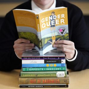 FILE - Amanda Darrow, director of youth, family and education programs at the Utah Pride Center, poses with books that have been the subject of complaints from parents on Dec. 16, 2021, in Salt Lake City. The nationwide surge in book bannings continues. The American Library Association reported Wednesday, Sept. 20, 2023, that challenges to books in schools and public libraries will likely reach record highs in 2023, topping what had been a record pace in 2022.  (AP Photo/Rick Bowmer, File)