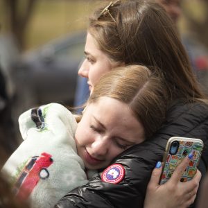 Two women hug after a school shooting at East High School Wednesday, March 22, 2023, in Denver. Two school administrators were shot at the high school Wednesday morning after a handgun was found on a student subjected to daily searches, authorities said. (AP Photo/David Zalubowski)