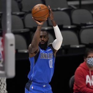 Dallas Mavericks forward Tim Hardaway Jr. (11) shoots as team owner Mark Cuban watches during the first half of the team's NBA basketball game against the Golden State Warriors in Dallas, Thursday, Feb. 4, 2021. (AP Photo/Tony Gutierrez)