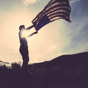 Man with American flag flying in the wind